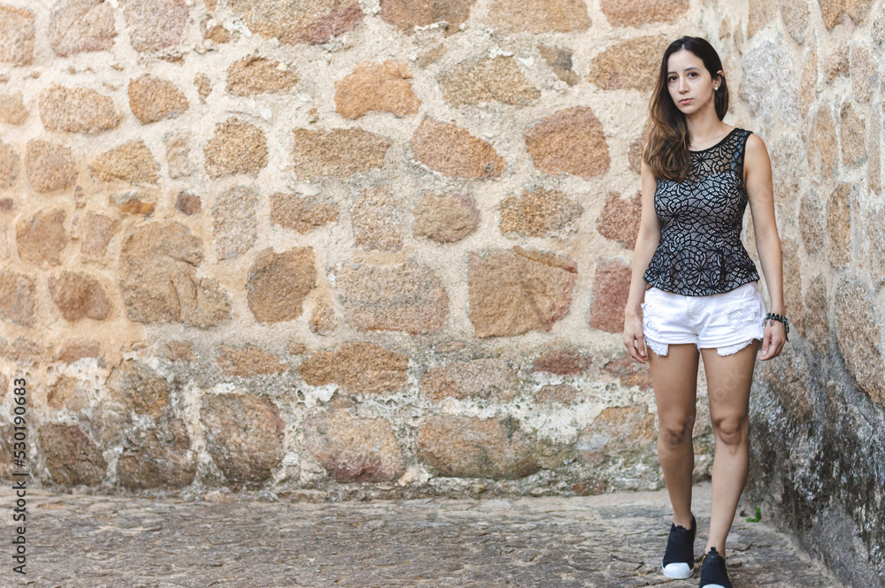 Portrait young attractive woman look at camera serious standing over isolated stone wall background Portrait young attractive woman look at camera serious standing over isolated stone wall background