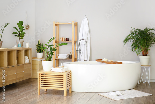 Interior of stylish bathroom with houseplants and shelving unit