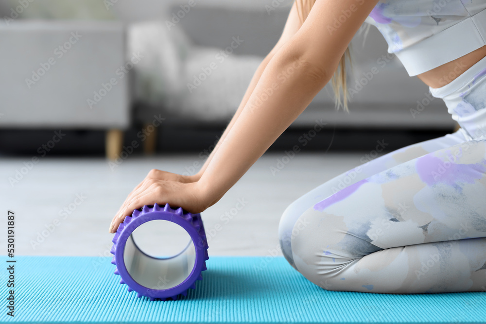 Young woman training with foam roller at home, closeup