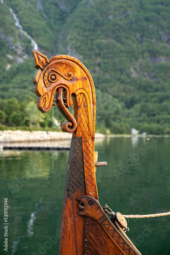 Dragon head at the front of a viking boat on the water photo