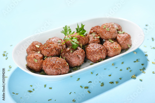 Plate with tasty meat balls and herbs on blue background © Pixel-Shot