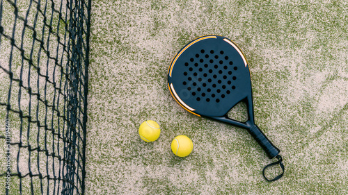 Fotografi Top view of yellow balls on floor near of padel tennis racket in green court
