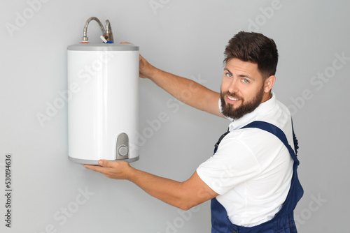 Male plumber installing boi...