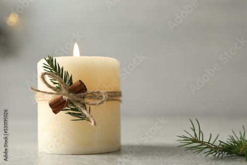 Burning candle with pinecone scent on light grey table, closeup. Space for text photo