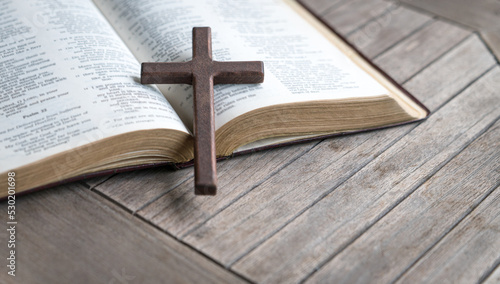 Foto Wooden cross on top of an open bible and wood table. Copy space.
