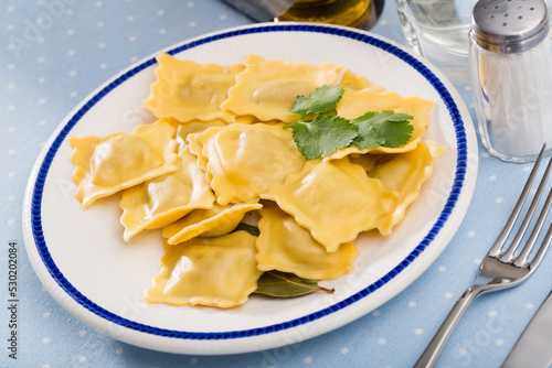 Homemade ravioli served with herbs on white plate