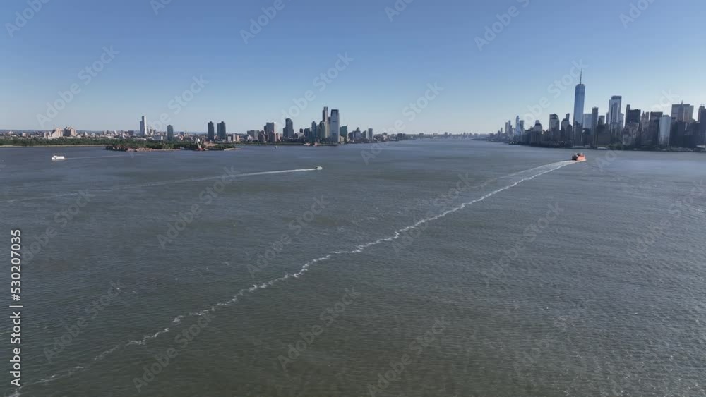 An aerial view of New York Harbor on a sunny day with clear blue skies. The drone camera truck right viewing New Jersey, lower Manhattan and Governors Island in the distance. An aerial view of New York Harbor on a sunny day with clear blue skies. The drone camera truck right viewing New Jersey, lower Manhattan and Governors Island in the distance.