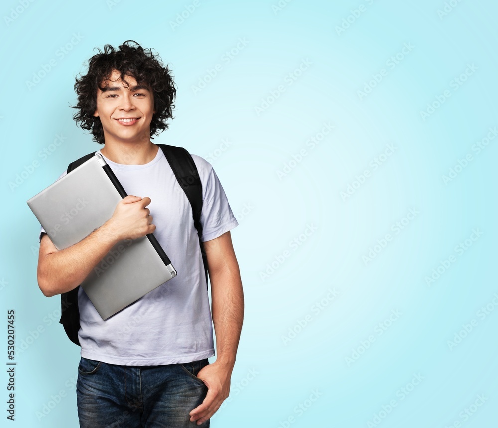 Cheerful young man standing and holding laptop pastel background. Cheerful young man standing and holding laptop pastel background.