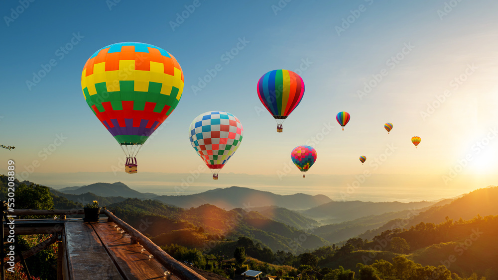 Obraz premium Colorful hot air balloons flying above mountain at sunrise sky background. Travel natural background.