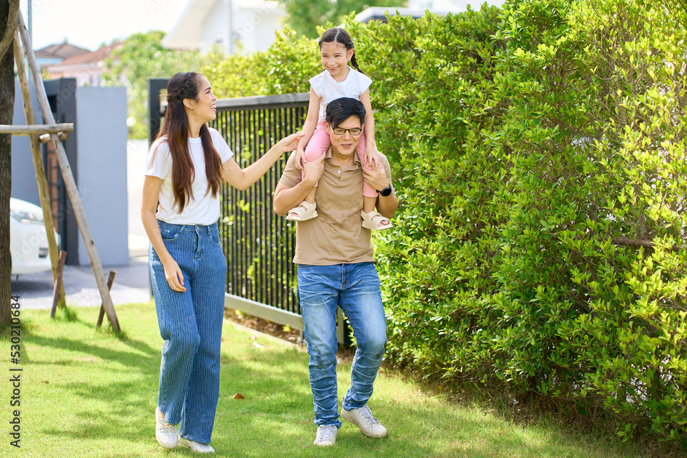 Fototapeta premium Asian family portrait with happy people smiling at the home garden,Daughter piggyback on her Dad ,Lifestyle and Holiday Family.