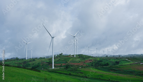 landscape of hills and wind turbines with misty foggy in morning time.