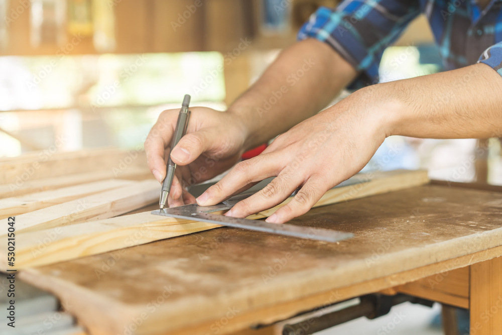 Carpentry professional, hand of asian young man, male carpenter use ruler measure, tool on board wood in small shop. Woodwork, furniture making, construction industry. Owner small business people. Carpentry professional, hand of asian young man, male carpenter use ruler measure, tool on board wood in small shop. Woodwork, furniture making, construction industry. Owner small business people.