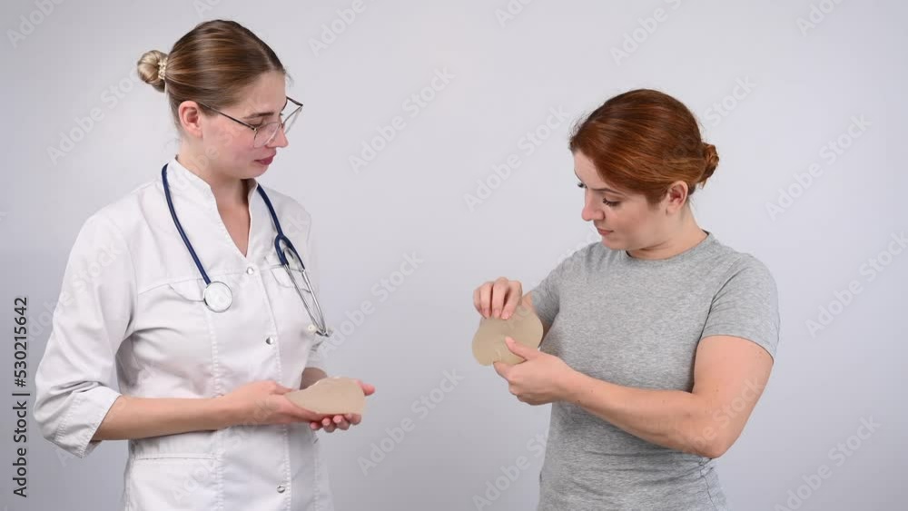 Caucasian woman and plastic surgeon choosing breast implants. Caucasian woman and plastic surgeon choosing breast implants.