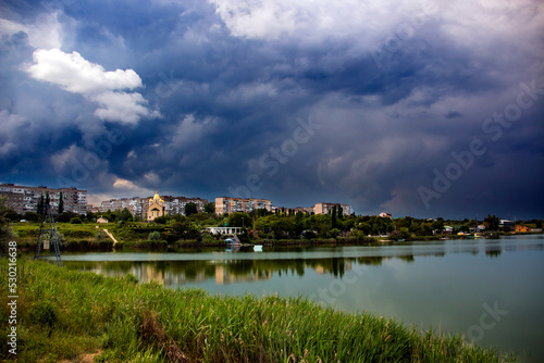 City houses under the sky before heavy rain next to the lake