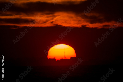 Large round orange sun at sunset over the sea horizon