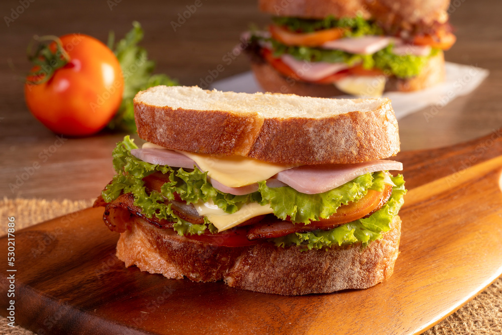 sandwich with ham and vegetables on a wooden table sandwich with ham and vegetables on a wooden table