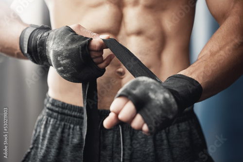 Training, fitness and boxing man prepare for workout or match at gym or fitness center with hand wrap. Closeup of athletic boxer getting ready for strength, cardio and endurance kickboxing challenge