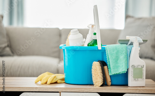 House  cleaning service and container with spray bottle  rubber gloves and scrub in home living room or apartment interior. Spring clean day  career or housekeeping with household products on table