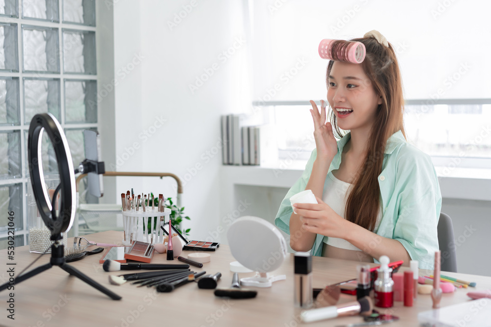 Beauty influencer concept, Young woman apply moisturizer cream on face to introduce product on Vlog