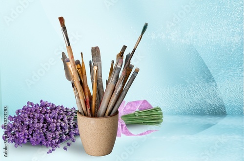 Set of paint brushes and lavender flower on desk