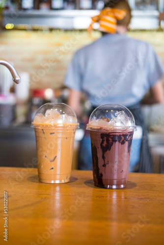 Iced chocolate and iced mocha on table with blurred back view of baretta at coffee shop photo