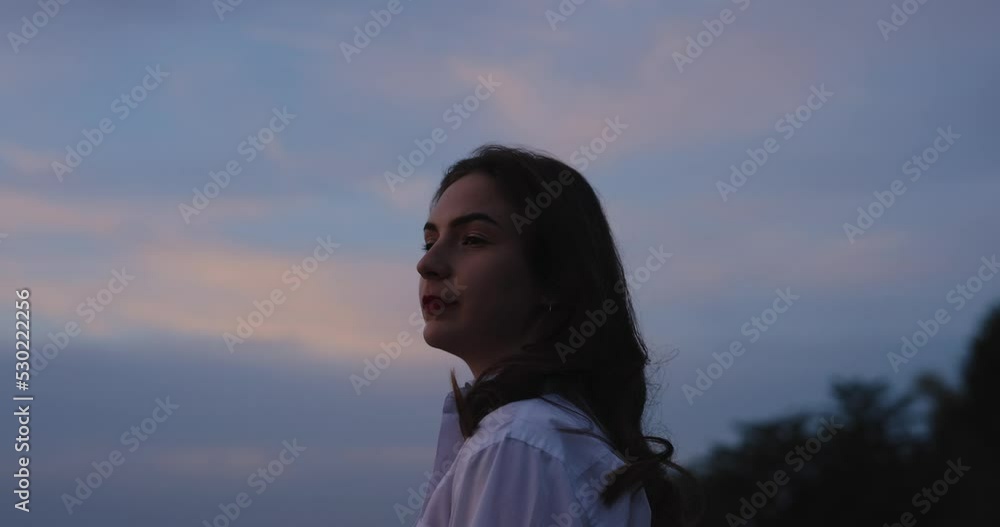 Silhouette of young woman walking on a hill at the evening looking at beautiful sea view Silhouette of young woman walking on a hill at the evening looking at beautiful sea view