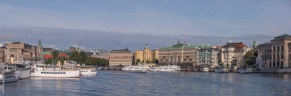 The bay Strömmen with hotels, steam boats and commuter boats at piers, a sunny autumn day in Stockholm