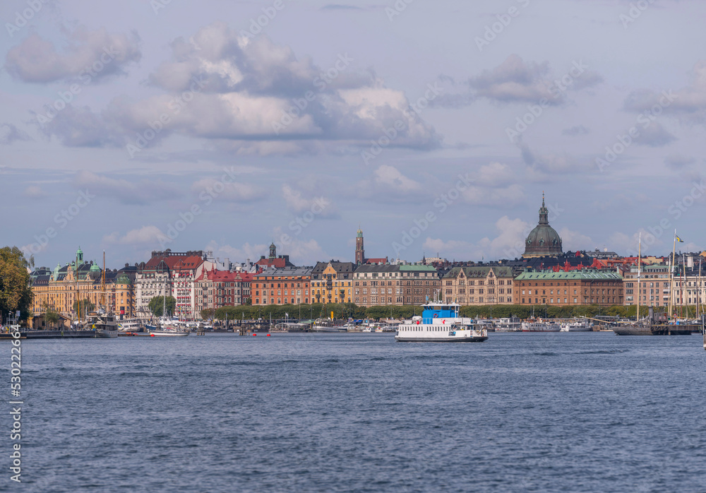 Panorama view over the bay Ladugårdsviken, commuter boats, sail boats, hotels, apartment houses and a harbor commuter ferry, a sunny autumn day in Stockholm