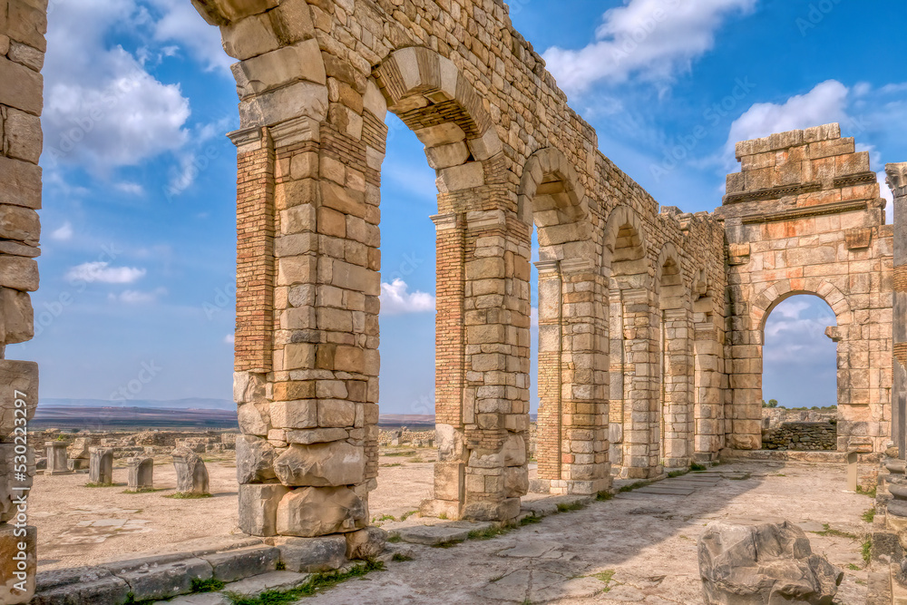 The brick and stone arched exterior wall of the basilica at restored Roman ruins at Volubilis, Morocco.