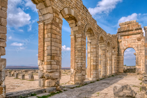 The brick and stone arched exterior wall of the basilica at restored Roman ruins at Volubilis, Morocco.