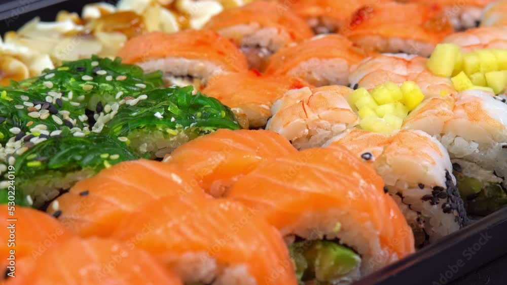 Japanese kitchen with sea food. Putting one sushi roll from set using sticks for sushi. Hand hold chopsticks with sushi roll. Philadelphia roll in sushi set close up. Traditional Japanese food. Japanese kitchen with sea food. Putting one sushi roll from set using sticks for sushi. Hand hold chopsticks with sushi roll. Philadelphia roll in sushi set close up. Traditional Japanese food.