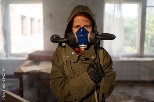 Post apocalypse female survivor in gas mask close up portrait in apocalyptic war, abandoned building on the background.