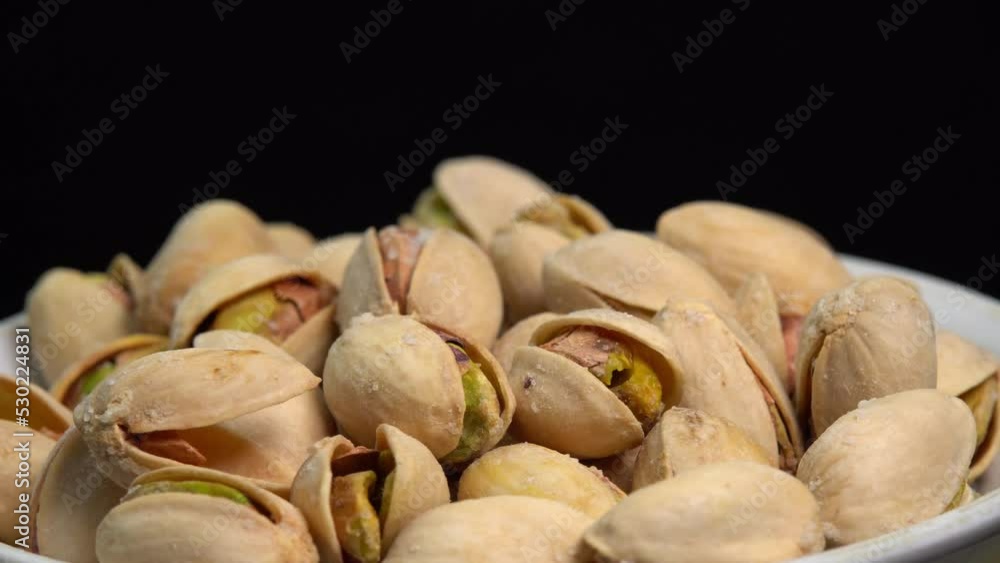 Salted pistachio nuts for beer background close up. Roasted pistachios rotate in a bowl on a black background. Vegan Healthy food high protein. Dietary nutrition. Concept of nuts. Salted pistachio nuts for beer background close up. Roasted pistachios rotate in a bowl on a black background. Vegan Healthy food high protein. Dietary nutrition. Concept of nuts.