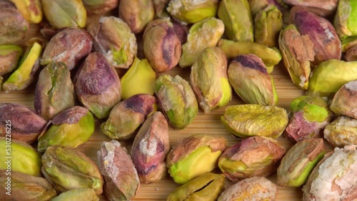 Pistachios without shells top view rotation. Pistachio nuts. Whole nut kernels. Pistachios kernels on wooden board. Roasted nuts with salt, nutrien snacks. High quality 4k footage photo