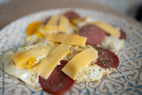 A plate of scrambled eggs with sausage and cheese.