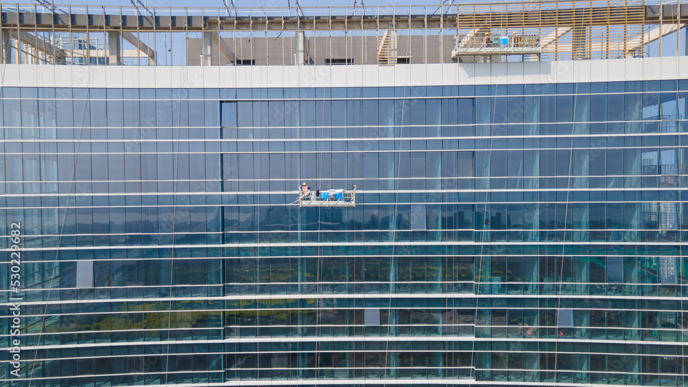 Aerial photography of cleaning workers (Spider-Man) cleaning the glass facade of the building Aerial photography of cleaning workers (Spider-Man) cleaning the glass facade of the building