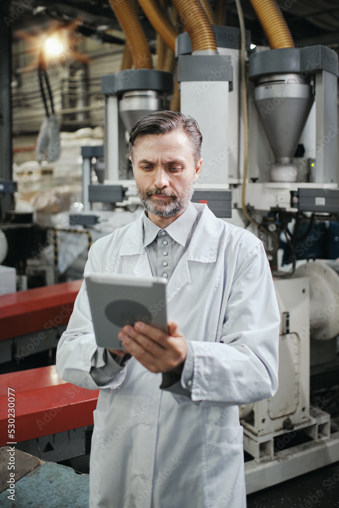 Engineer with tablet working at polymer factory Engineer with tablet working at polymer factory