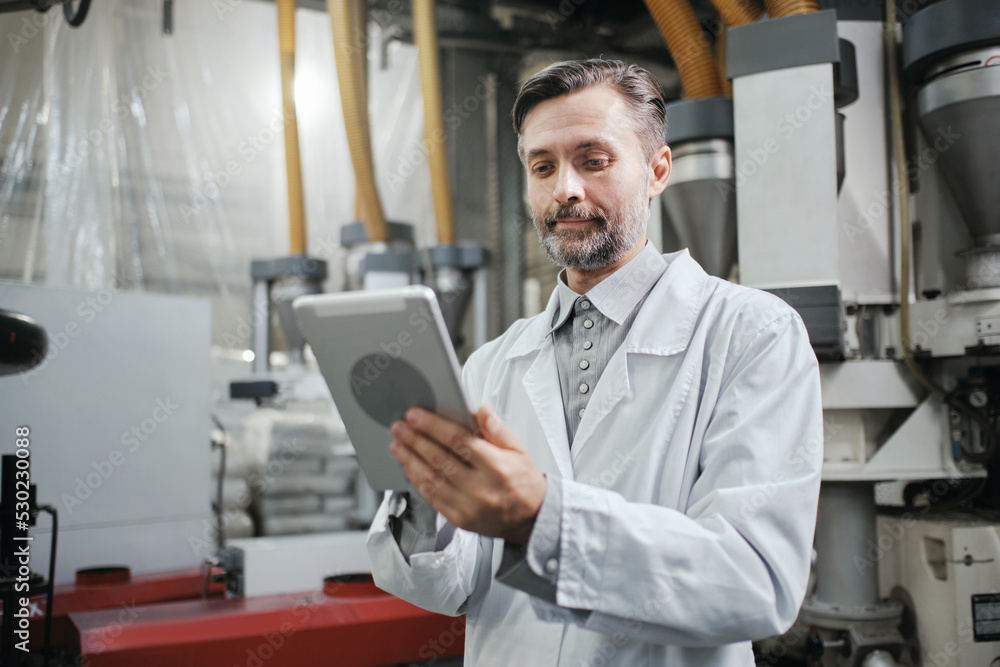 Fototapeta premium Engineer with tablet working at polymer factory