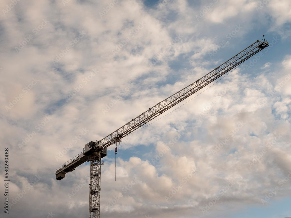 Silhouette of a tall crane against cloudy sky. Construction industry.