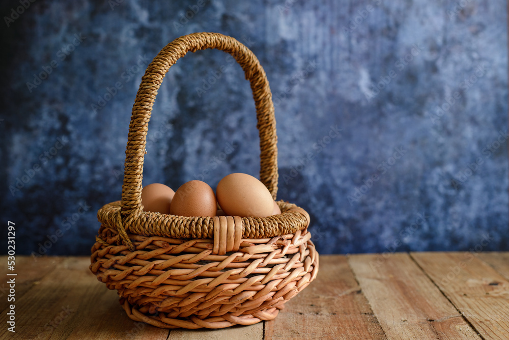 Farm fresh eggs in a wicker basket. Blue background.