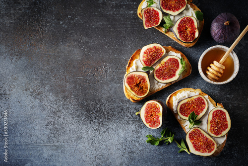 Fig bruschetta, bread and cream cheese and fruit on dark background