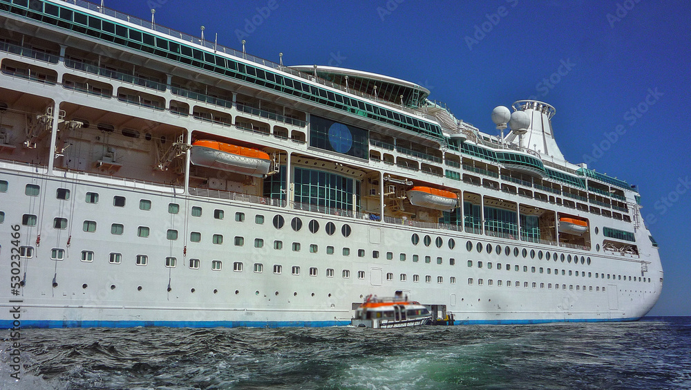 Obraz premium Traumreise Karibikkreuzfahrt mit Kreuzfahrtschiff - White cruiseship cruise ship anchoring at sea tendering passengers to tropical island during Caribbean cruising