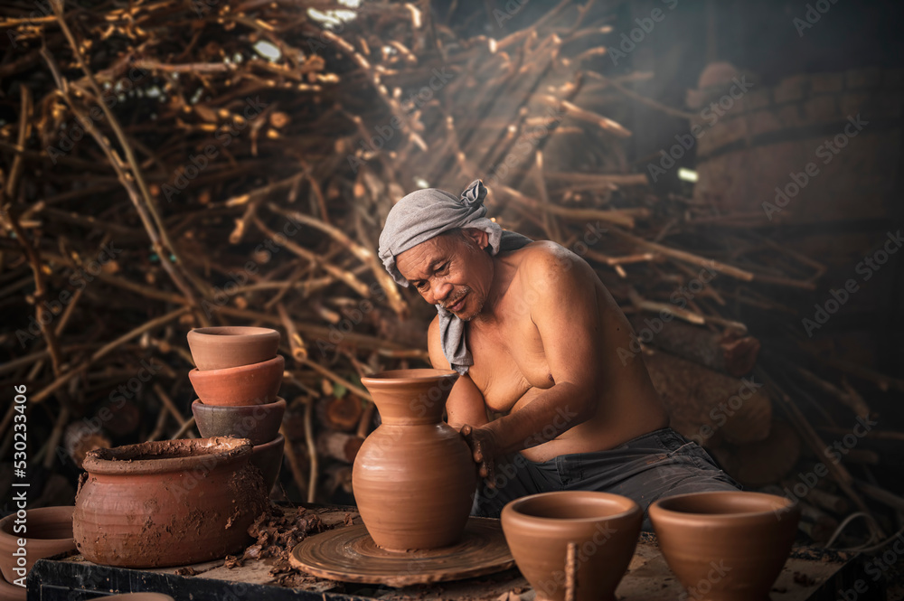 A senior man is using a potter's wheel to make pottery from wet clay. A senior man is using a potter's wheel to make pottery from wet clay.