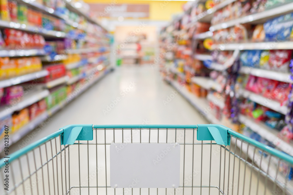 Empty shopping cart in department store with blurred background of shelves.