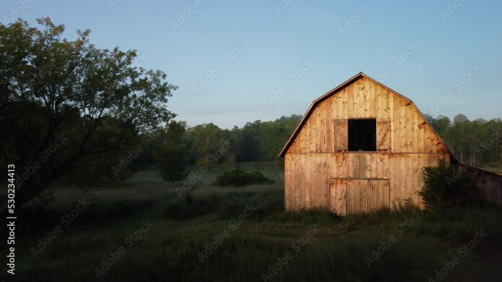 Sun lit barn foggy morning, in summer countryside, aerial rise up wide shot Sun lit barn foggy morning, in summer countryside, aerial rise up wide shot