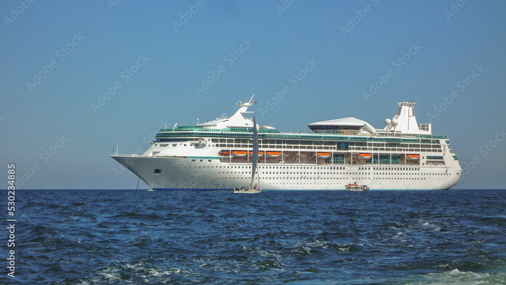 Traumreise Karibikkreuzfahrt mit Kreuzfahrtschiff - White cruiseship cruise ship anchoring at sea tendering passengers to tropical island during Caribbean cruising Traumreise Karibikkreuzfahrt mit Kreuzfahrtschiff - White cruiseship cruise ship anchoring at sea tendering passengers to tropical island during Caribbean cruising