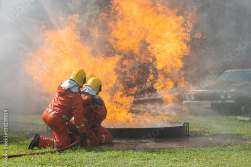 Firefighters wearing helmets with fire safety equipment Use Twirl aerosol fire extinguishers to fight oil flames.Preventing fire accidents is an industrial safety concept.