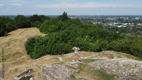 Girl site seeing at St. Martin's Hill (Góra Św. Marcina (Zabłocie)) in Tarnów, Poland. Site of the Tarnowski Castle ruins, the remnants of Tarnow's first settlements - 4K 30FPS Drone Tracking Left photo