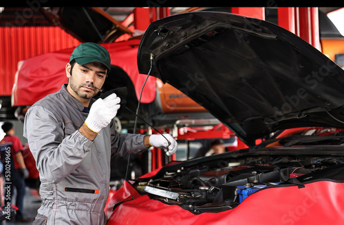 Man working in automobile restoration workshop. Checking oil in car engine