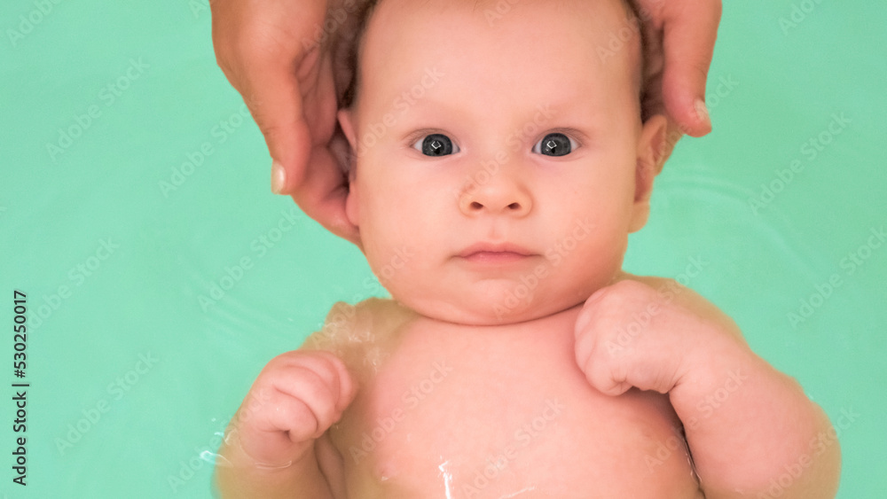 Mother teaches a newborn baby to swim and stay on the water. Twomonth